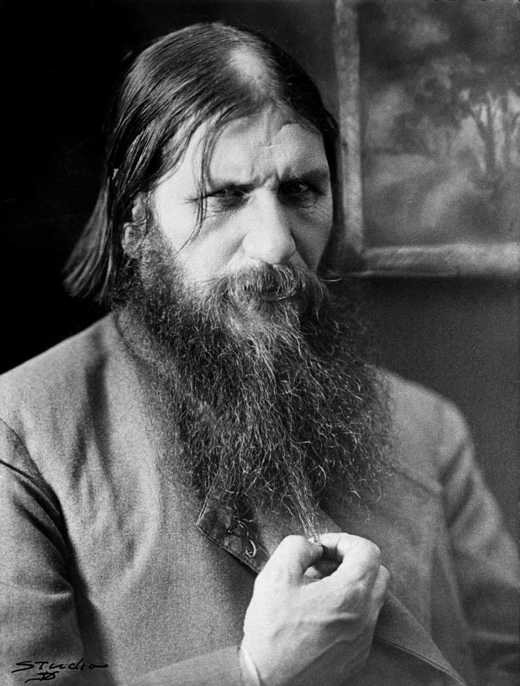 Rasputin in 1916 playing with his beard