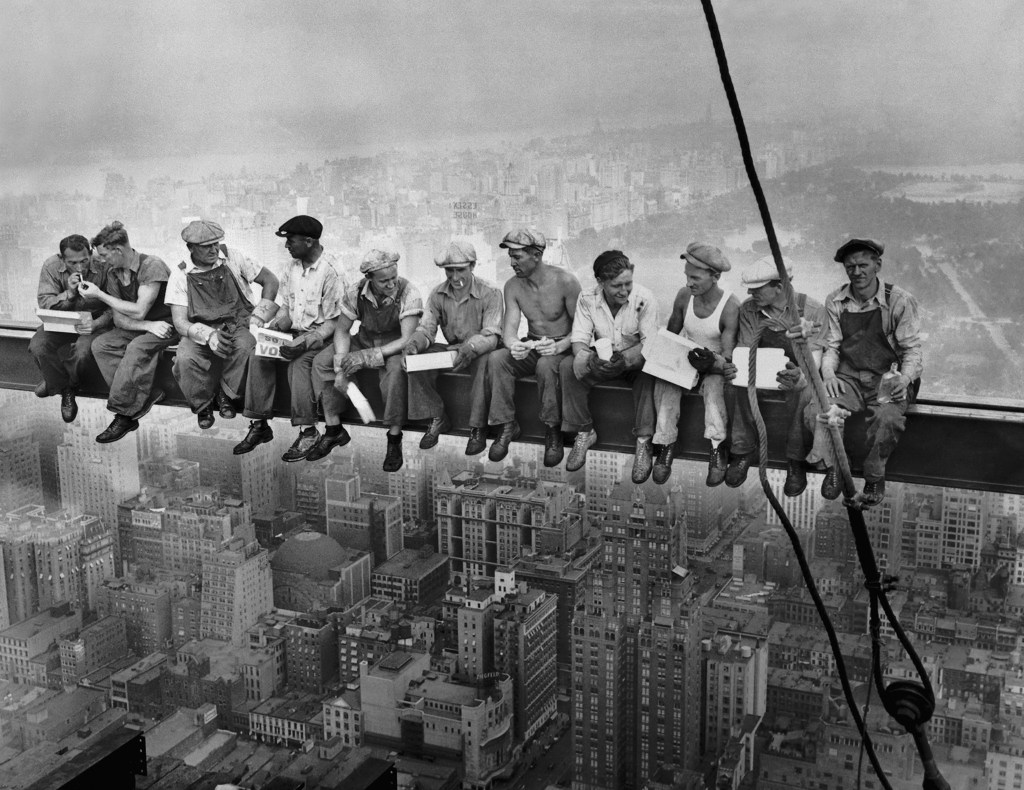 The famous historical photograph, Lunch atop a skyscraper showing workers sitting on a steel beam above the skyline of Manhattan in 1932.