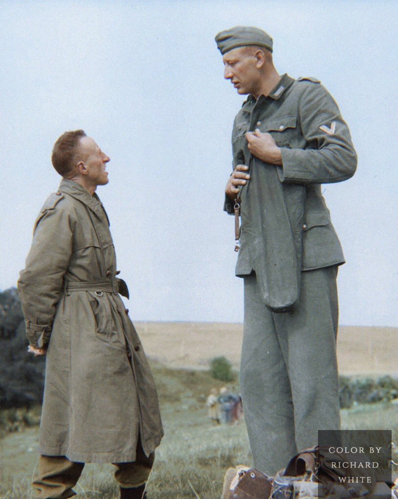 The tallest soldier to fight in World War 2, Jakob Nacken wearing his military uniform talking with a Canadian soldier wearing a trench coat in September 1944. The photograph is colorized