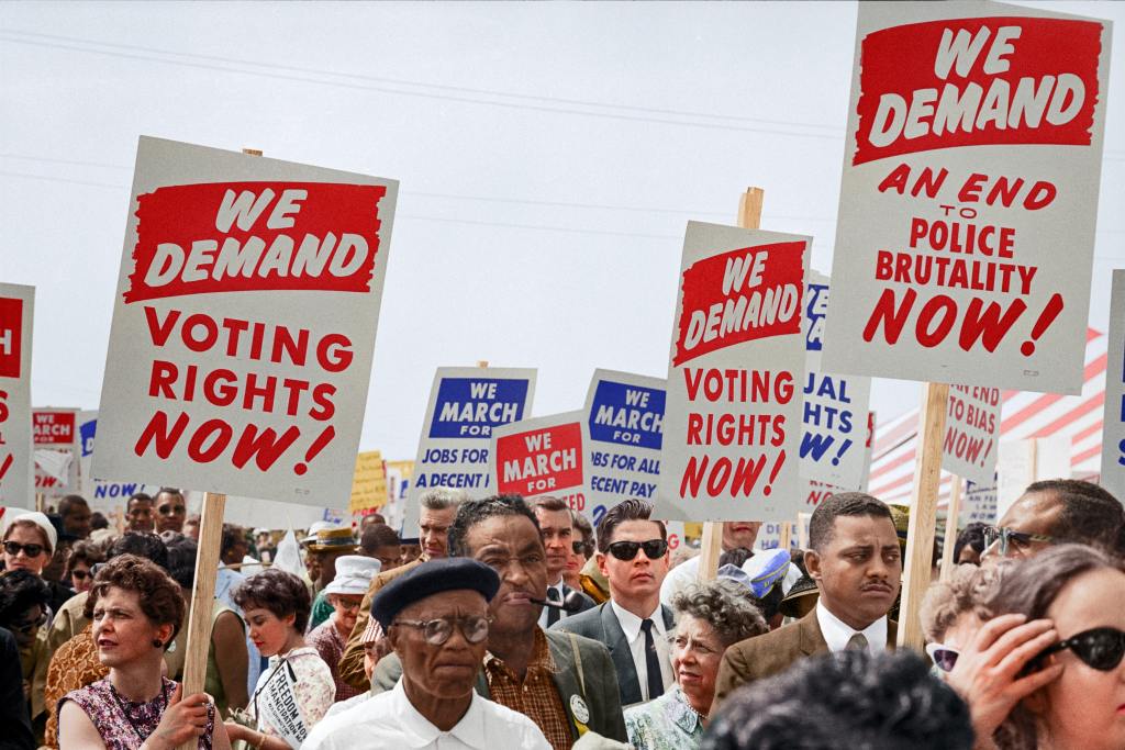 Color photograph of a crowd at the March on Washington showing some of the signs that were held