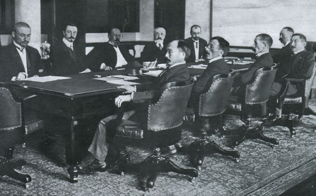 Treaty of Portsmouth delegations: Russians (far side of table) -- Korostovetz, Nabokov, Witte, Rosen, and Plançon; and Japanese (near side of table) -- Adachi, Ochiai, Komura, Takahira, and Sato.
