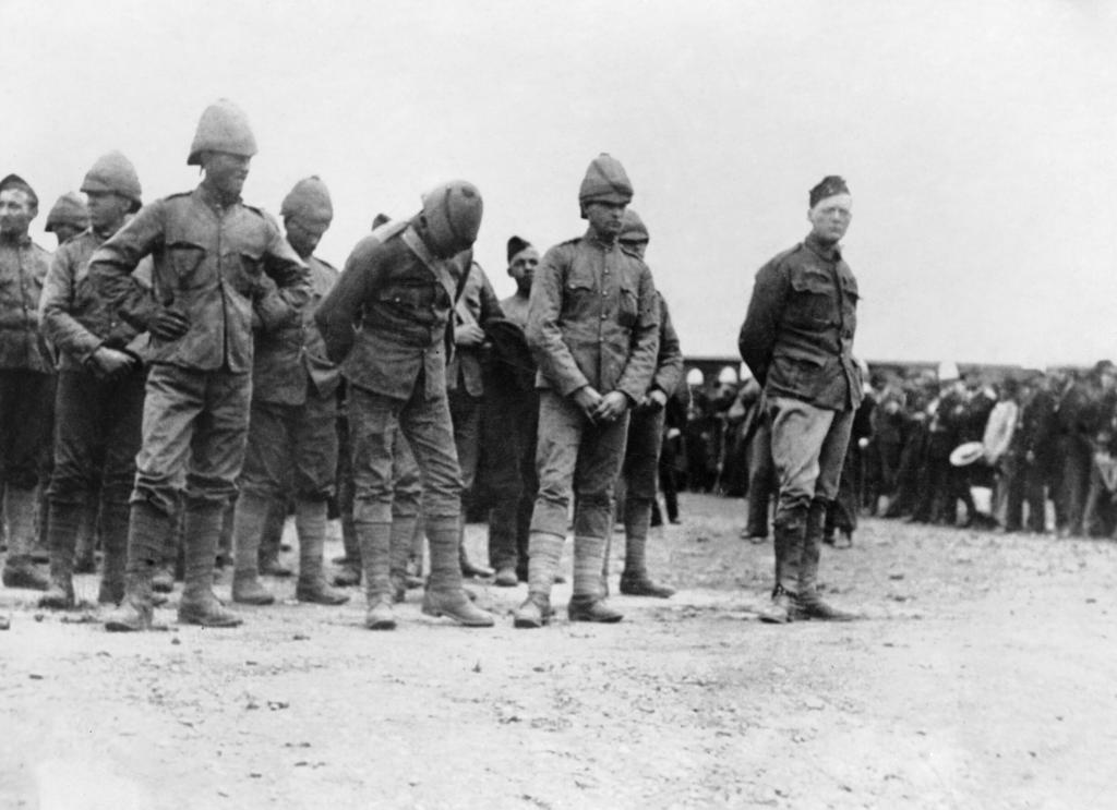 Winston Churchill wearing a uniform standing on the right of a group of prisoners during the Second Boer War, 1899.