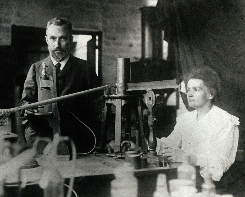Pierre and Marie Curie in the laboratory, demonstrating the experimental apparatus used to detect the ionisation of air, and hence the radioactivity, of samples of purified ore which enabled their discovery of radium.