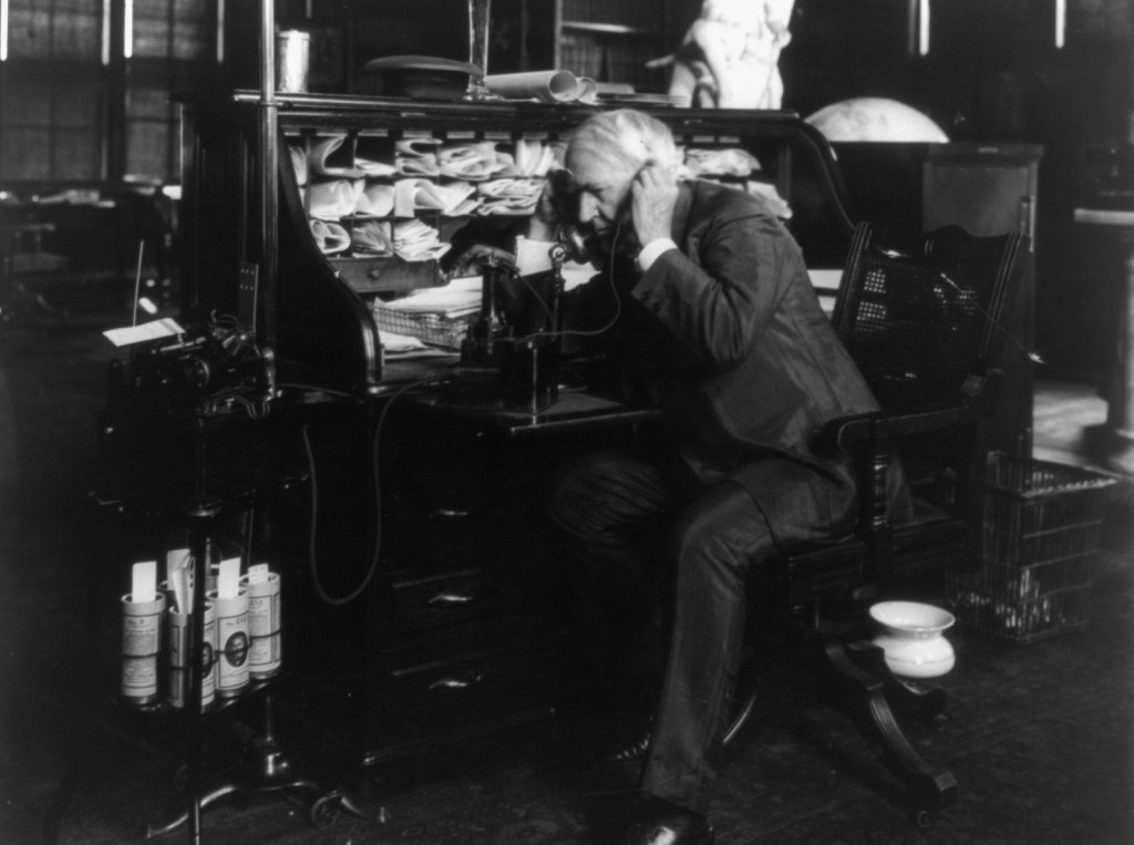 Thomas Edison using a telephone