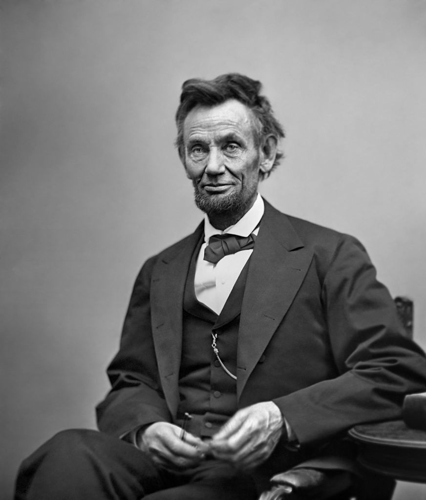 Abraham Lincoln, three-quarter length portrait, seated and holding his spectacles and a pencil in 1865