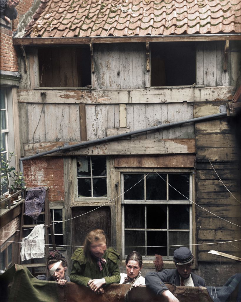 Four women photographed outside a house in the slums of Amsterdam, the Netherlands in 1899. The photograph was taken by the Health Service in preparation for an uninhabitable declaration. Photograph colorized by Baptiste Pierre