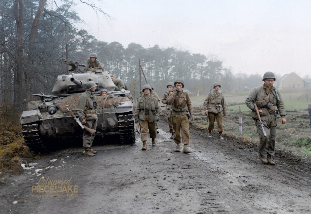 GI's of the 1st Battalion, 120th Regiment, 30th Infantry Division pass a M24 Chaffee, probably of the 744th Tank Battalion, in pursuit of the fleeing 116th Panzer Division.

The front hull of the M24 is covered with dirt from burst sandbags, indicating it had engaged the enemy.
26 March 1945, Wesel forest, Germany.
Colorized by Colourised Piece of Jake