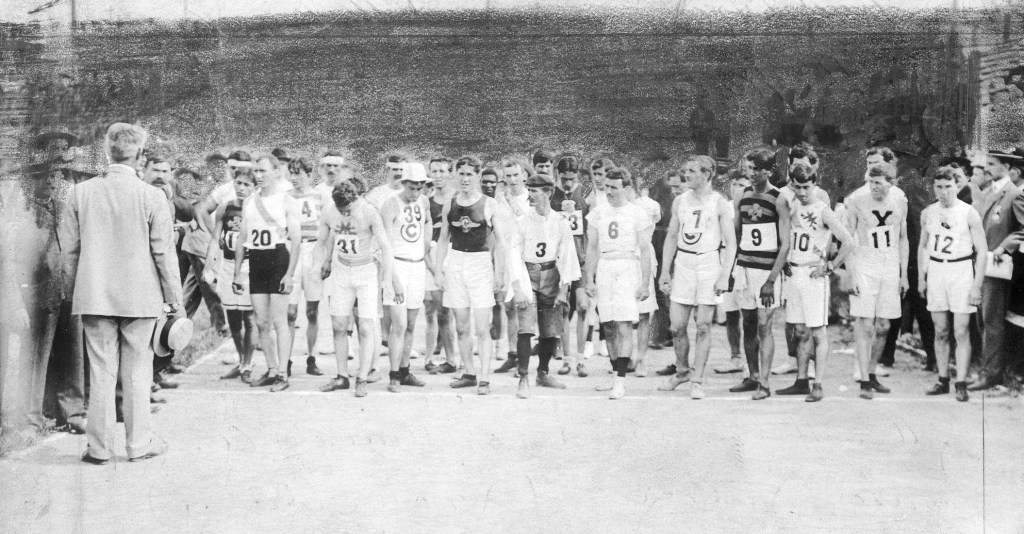 Olympic marathon runners at the start line receiving instructions before the race begins.
Thomas Hicks (20), Fred Longm (31), S. H. Holt (39), Felix Caravajal (3), Christos D. Zehouritis (6), Albert L. Cory (7), Frank Pierce (9), S. A. Mellor (10), Edward P. Car (11) feature in the photo.