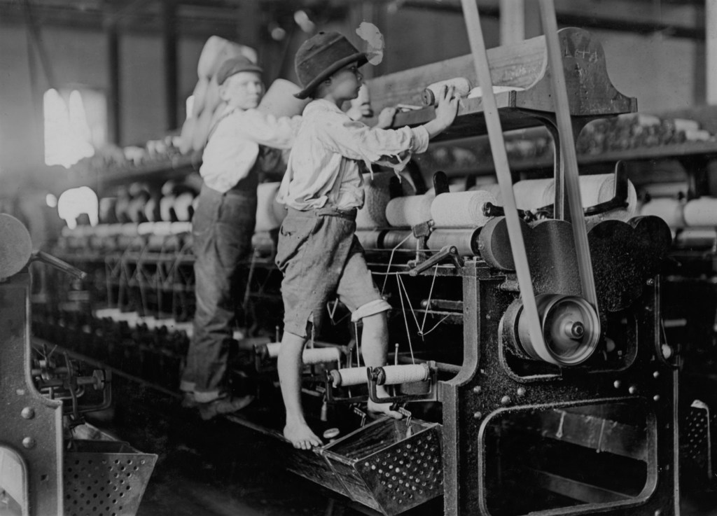 Original Child Labor Committee description: 488 Macon, Ga. Lewis W. Hine 1-19-1909. Bibb Mill No. 1 Many youngsters here. Some boys were so small they had to climb up on the spinning frame to mend the broken threads and put back the empty bobbins. Location: Macon, Georgia.