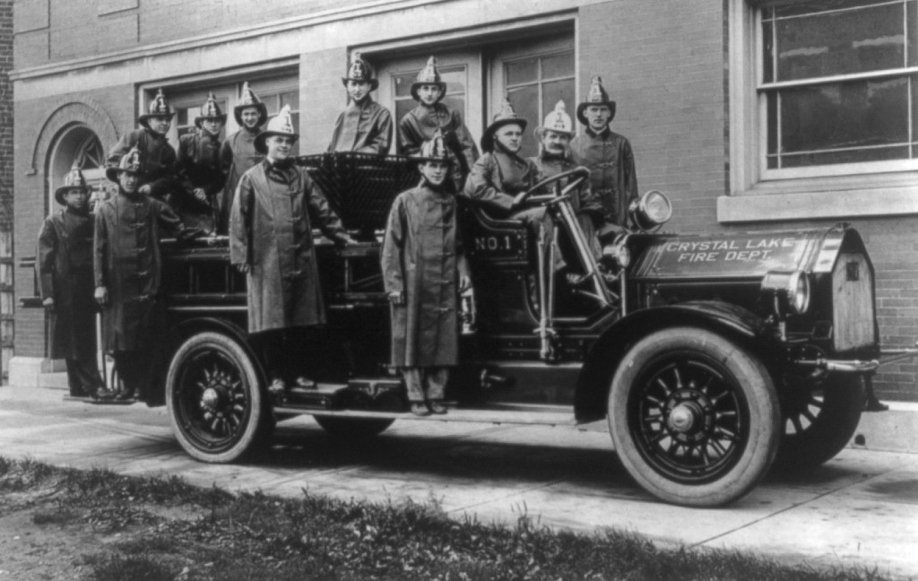 black and white photograph of a fire crew of Crystal Lake Fire Dept. in uniform and helmets posing with their fire engine