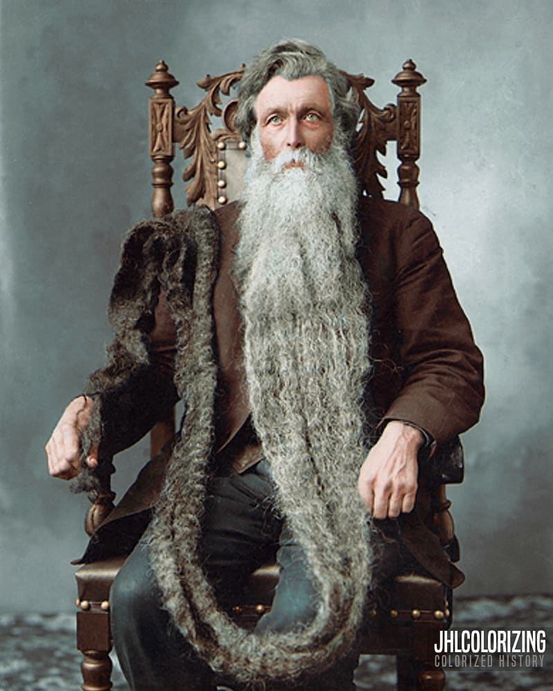 Colorized photograph of Hans Langseth, the man who held the record for the world's longest beard, sitting in a chair and showing off his long beard.
