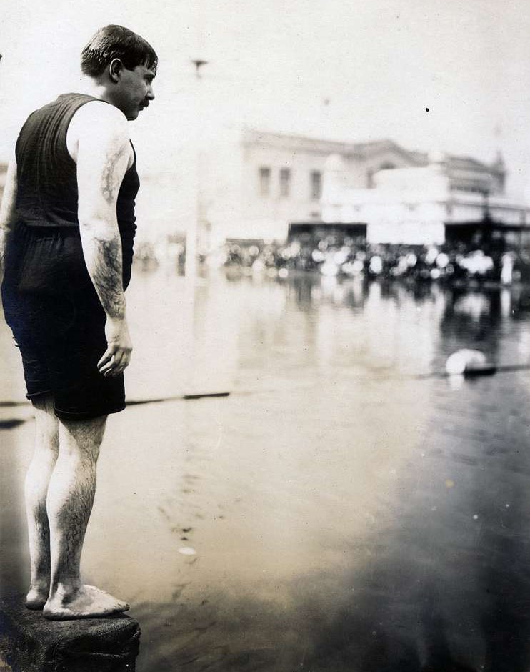 Vertical photograph of a wet man standing on a block above water.Title: W.E. Dickey of the New York Athletic Club, winner of the Plunge for Distance competition at the 1904 Olympics with a distance of 62 feet, 6 inches.