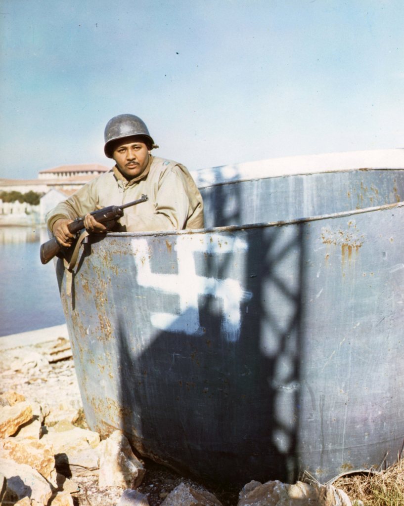 Capt. James H. Page, Los Angeles, California, attached to the 92nd (Negro) Div., Medical Supply, stands in an incompleted ship turret bearing Nazi emblem in a shipyard near Viareggo, Italy.